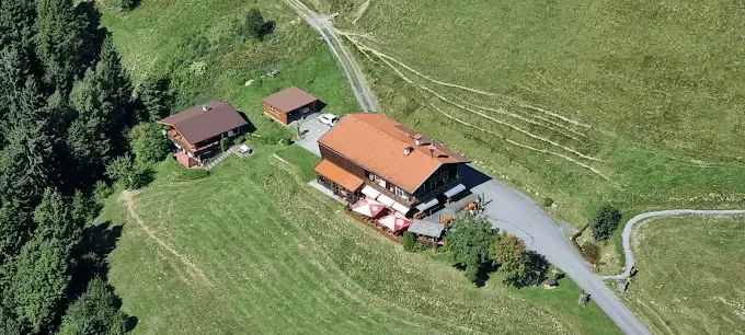 Luftaufnahme der Tennalm im Sommer, umgeben von grünen Almwiesen