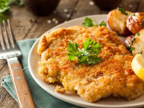 Paniertes Schnitzel mit Petersilie und Röstkartoffeln auf einem Teller